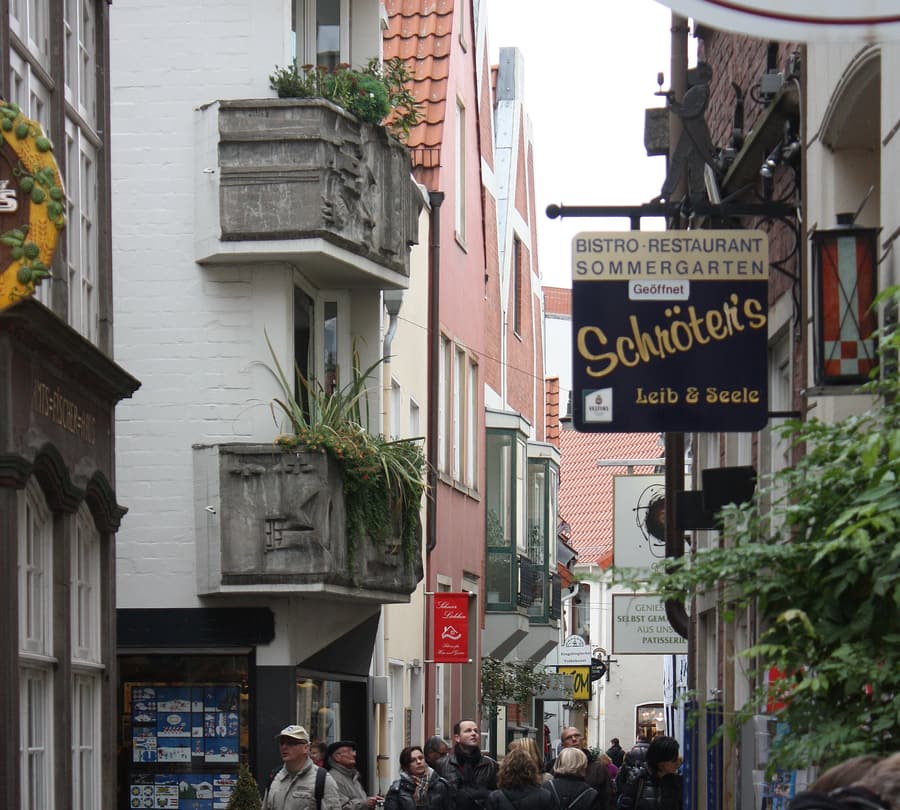 Enge Gasse im Schnoorviertel in Bremen-Mitte mit dicht aneinandergebauten historischen Häusern und geschnitzten Balkonen