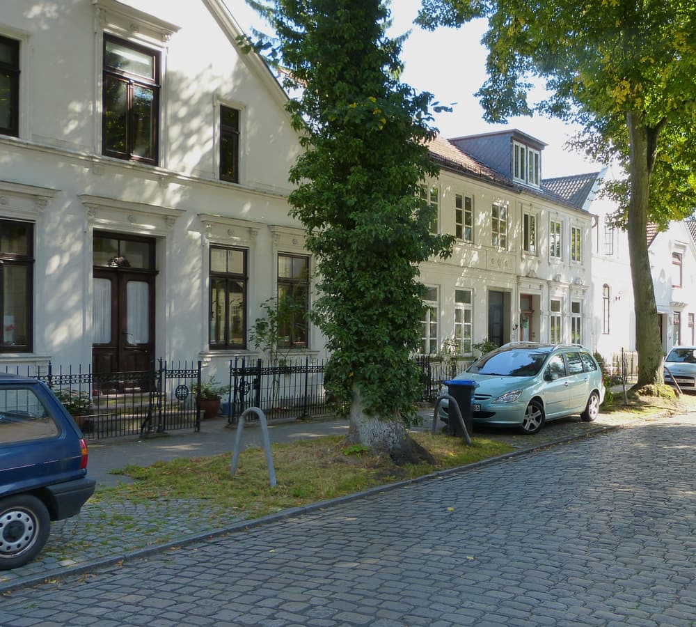 Klassizistische Kapitänshäuser in der Weserstraße in Bremen-Vegesack, gesäumt von alten Bäumen und Kopfsteinpflaster